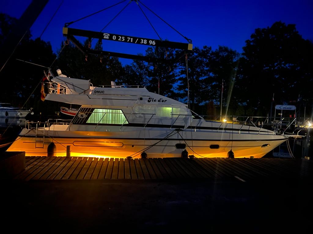 Luxusboot im Hafen bei Nacht, beleuchtet mit warmem Licht.