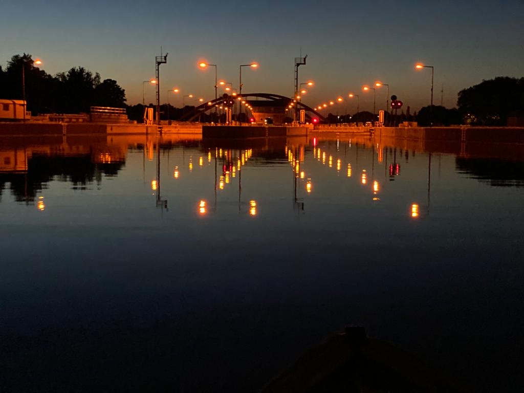 Ein ruhiger Wasserbereich mit reflektierenden Lichtern in der Dämmerung.