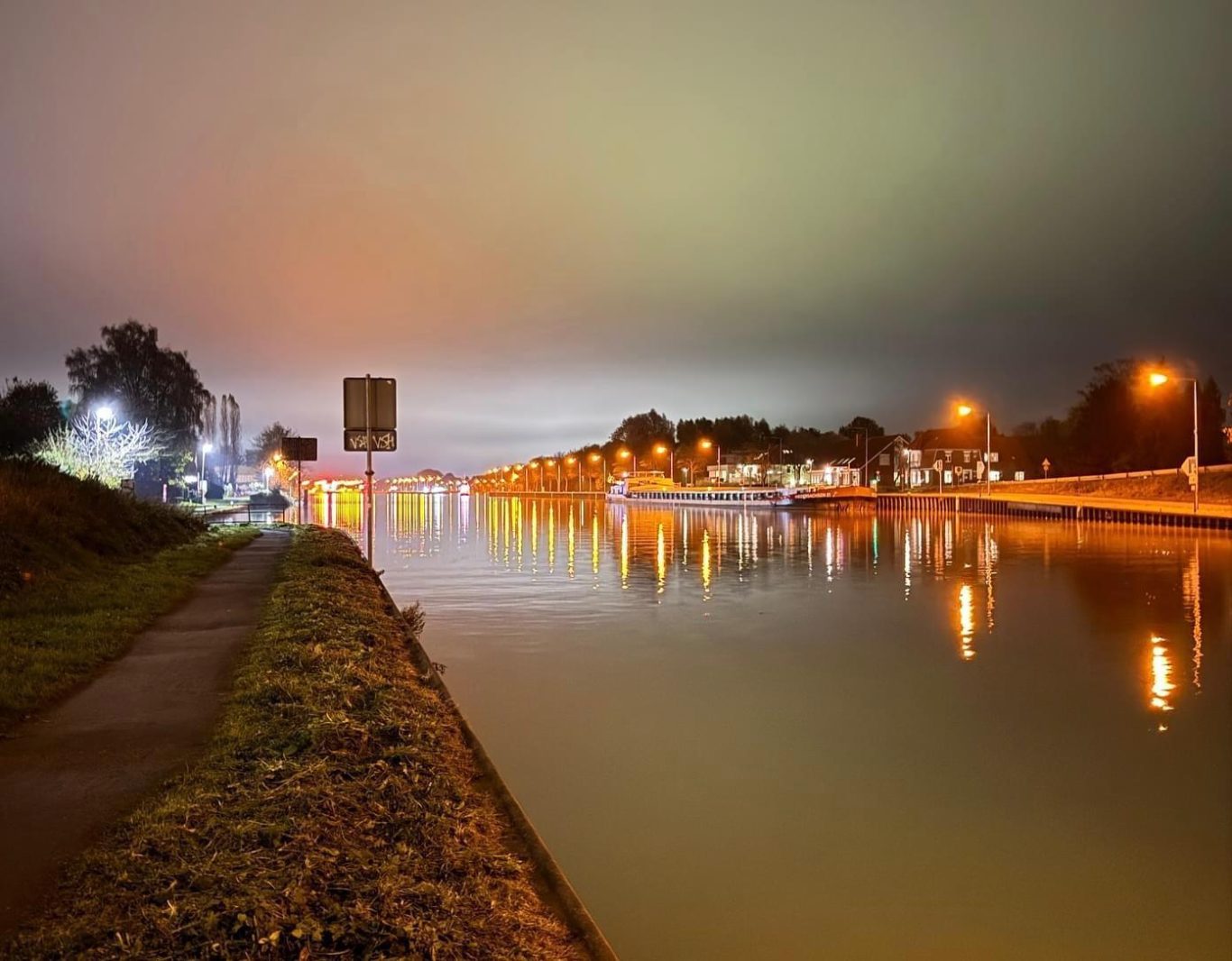 Fließender Fluss bei Nacht, beleuchtet von Stadtlichtern und sanften Wolken.