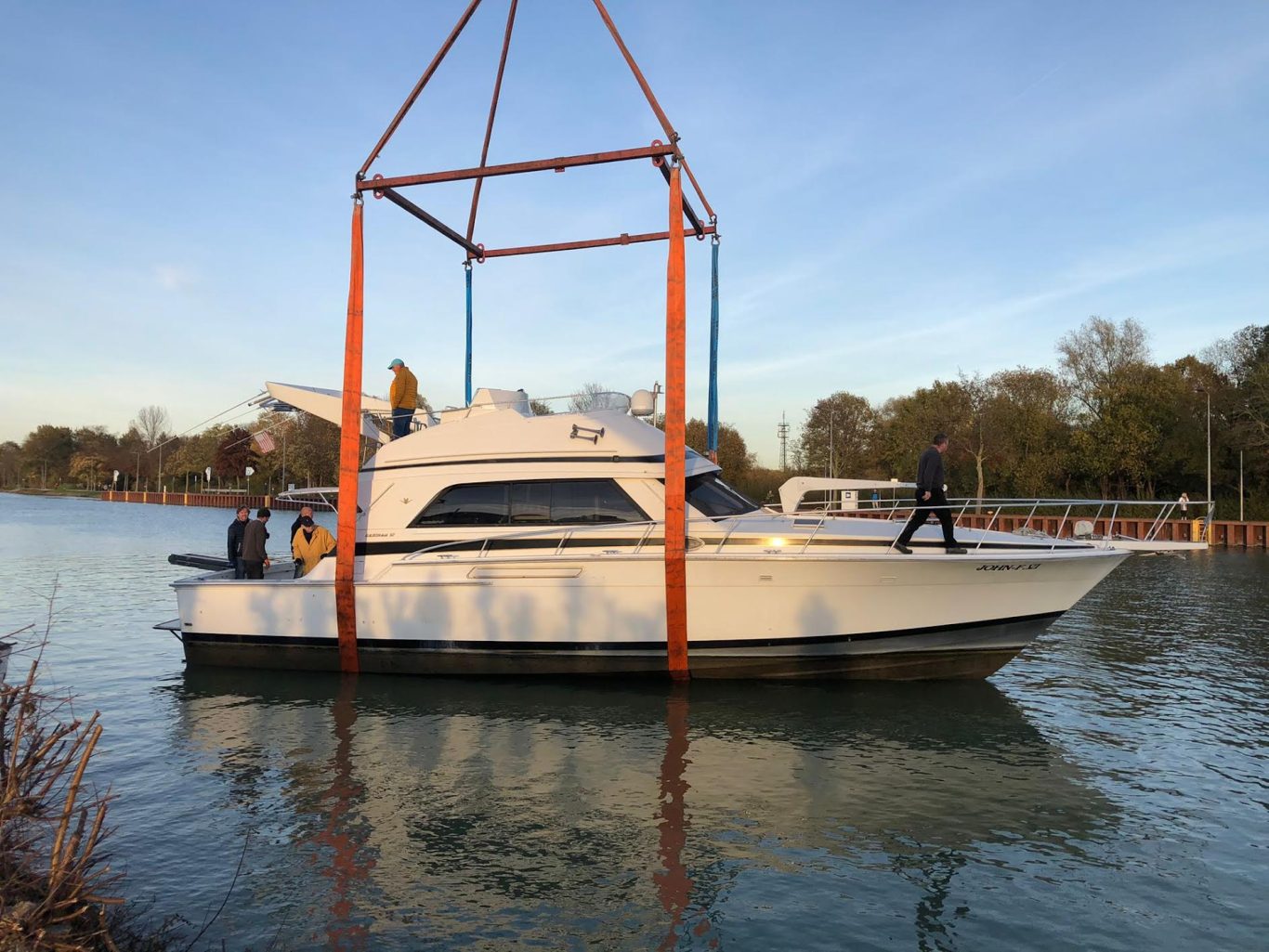 Ein Boot wird von einem Kran über Wasser gehoben, um es an Land zu bringen.